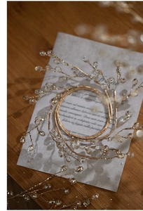 Close-up of golden beaded wreath ornament with glitter acrylic droplets on wood