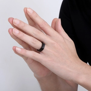 Macro close-up of a minimalist black stainless steel ring with flat faceted surface