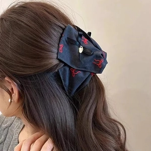 Detailed back view of a large navy blue bow hair claw with embroidery and gold pendant