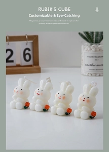 Detail of four white rabbit scented candles with orange flower accents and minimal tags