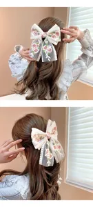 Detail of lace embroidered oversized bow hair clip with floral rose patterns