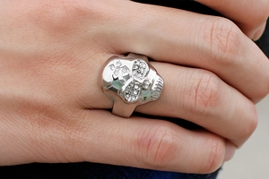 Macro shot of stainless steel skull ring with crystal eyes and cross engraving on finger