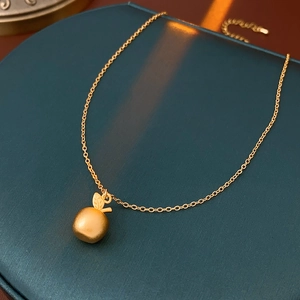 Detail of 18k gold plated apple pendant with matte texture and delicate O-chain