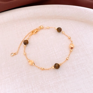 Détail de la pierre d'oeil de tigre et des perles en métal doré sur le bracelet