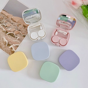 Detail view of macaron colored contact lens cases with tweezers and suction tool kit