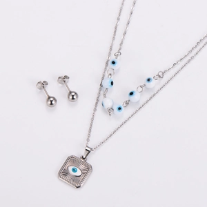 Detail of double-layer stainless steel necklace with square evil eye charms and stud earrings