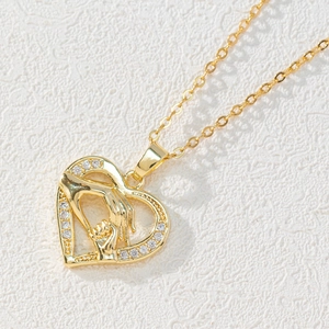 Detailed macro view of a 18k gold heart pendant featuring a mother and child holding hands
