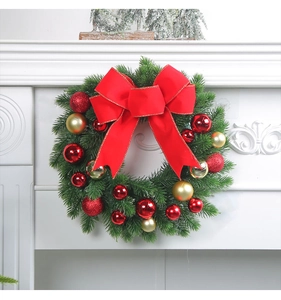 Detailed view of a Christmas wreath with red bows and gold ornaments on a fireplace