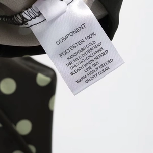 Detail des Pflegeetiketts aus 100 % Polyester mit Waschanleitung auf Satin-Stoff