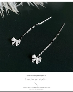 Detailed macro view of S999 sterling silver bow tassel earrings with a textured finish