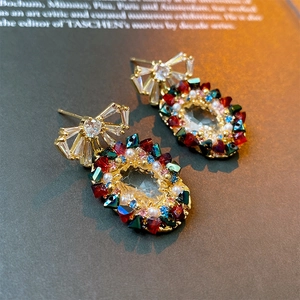 Macro detail of vintage gold bow earrings with colorful crystals on a dark book