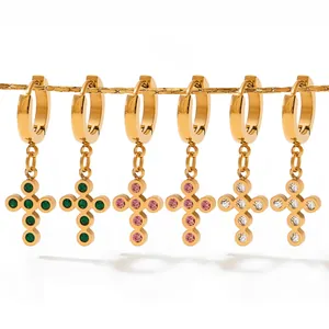 Detailed close-up of baroque gold cross earrings with colorful zircon stones on gold chains