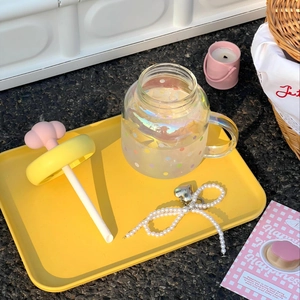 Cloud-shaped glass cup with rainbow finish and polka dots on a yellow tray with straw