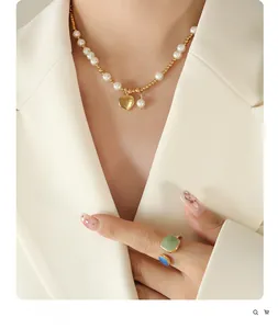 Detail of beaded pearl necklace with heart pendant and green gemstone open ring on model