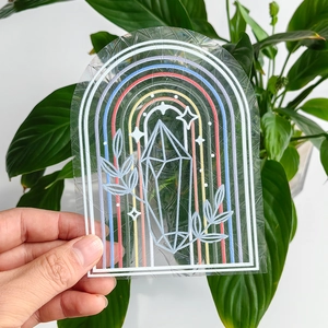 Detail of transparent rainbow prism suncatcher sticker with white leaf and crystal art