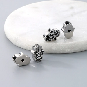Detailed view of silver Hamsa hand charms with embossed vintage patterns for bracelets