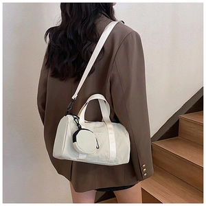 Close-up of off-white cylindrical crossbody bag with mini pouch and jacquard strap