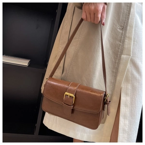 Detail of vintage brown leather shoulder bag with gold square buckle and minimalist strap
