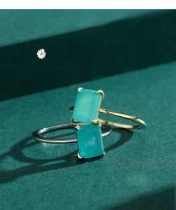 Nahaufnahme von silbernen und goldenen Ringen mit grünem Stein in Vier-Krallen-Einstellung