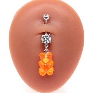 Detail of silver belly ring with double cubic zirconia and orange gummy bear charm
