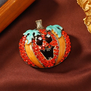 Close-up of Halloween pumpkin brooch with orange rhinestones on silk background