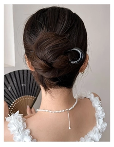 Pic à cheveux en U noir élégant porté en chignon avec collier de perles