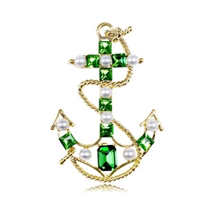 Detailed shot of golden anchor brooch with green gemstones and white pearls inlay