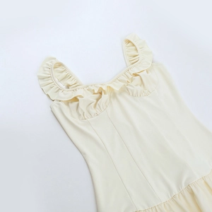Detailed view of ruffle neckline and dual straps on light beige sleeveless mini dress