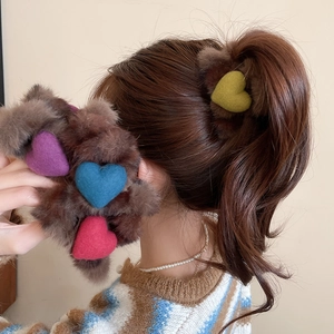 Vue détaillée d'un chouchou en peluche marron avec des cœurs en feutre colorés dans une queue