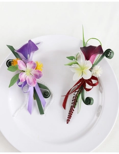 Close-up of calla lily boutonnieres with pearls and ribbons on a white ceramic plate