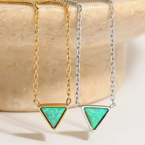 Gold and silver triangle green opal necklaces displayed on a marble textured surface