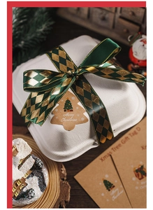 Close-up of Christmas tree gift tag on biodegradable box with dark green satin ribbon