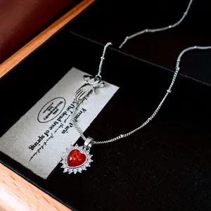 Vintage silver necklace featuring a red heart zircon pendant and hand-shaped charm