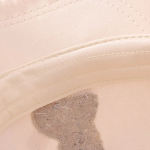 Close-up of the smooth stitching and interior sweatband of the beige cotton baseball cap