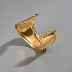 Detail of high-polished 18K gold plated wide wave cuff bracelet with mirror finish