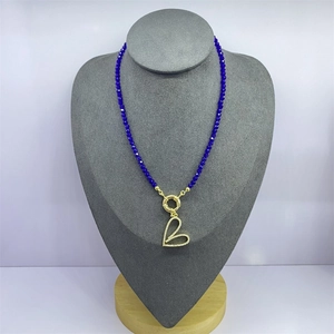 Detail of dark blue crystal necklace with a gold heart pendant and zircon inlay