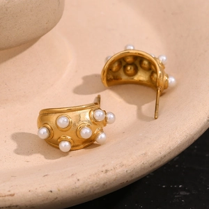 Détail de boucles d'oreilles lune dorées 18K avec perles blanches dans un plat bio