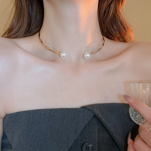Détail d'un collier ras du cou doré ondulé avec perles sur le cou d'un mannequin