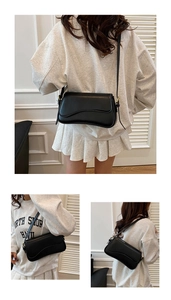 Detail view of stylish black leather crossbody bag with adjustable gold buckle hardware
