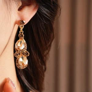 Gros plan de boucles d'oreilles vintage dorées avec strass champagne portées par un mannequin
