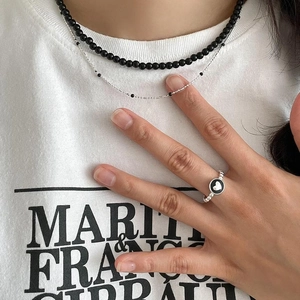 Detail of S925 silver heart ring and layered necklace with black beads on a model
