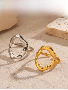 Detail view of gold and silver irregular hollow geometric rings on a stone display