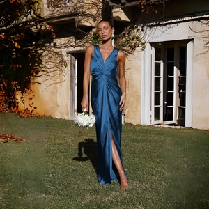 Détail d'une robe élégante en satin bleu foncé avec col en V et nœud à la taille