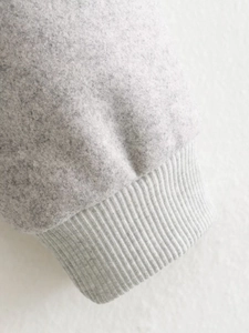 Gros plan sur la texture molletonnée gris clair et les poignets élastiques côtelés