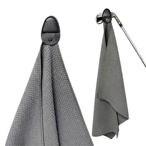 Dark grey waffle weave golf towel with magnetic leather strap hanging on a golf club