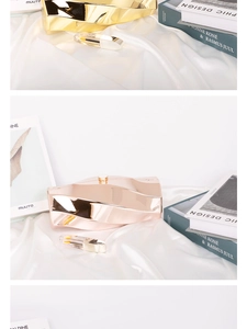 Macro view of geometric ripple metal evening bag in champagne gold with a mirror finish