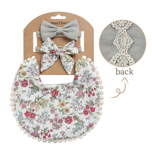 Detail of floral baby bib and bow headband set with elegant white lace back and pompom trim