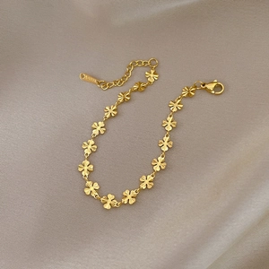 Detailed close-up of golden clover chain bracelet made of brushed stainless steel