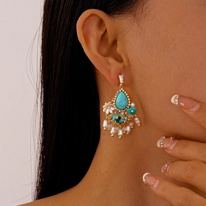 Detail of vintage gold flower earrings with turquoise accents and dangling pearls
