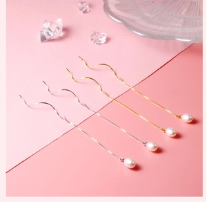 Detail of silver and gold pearl drop earrings on a pink minimalist background